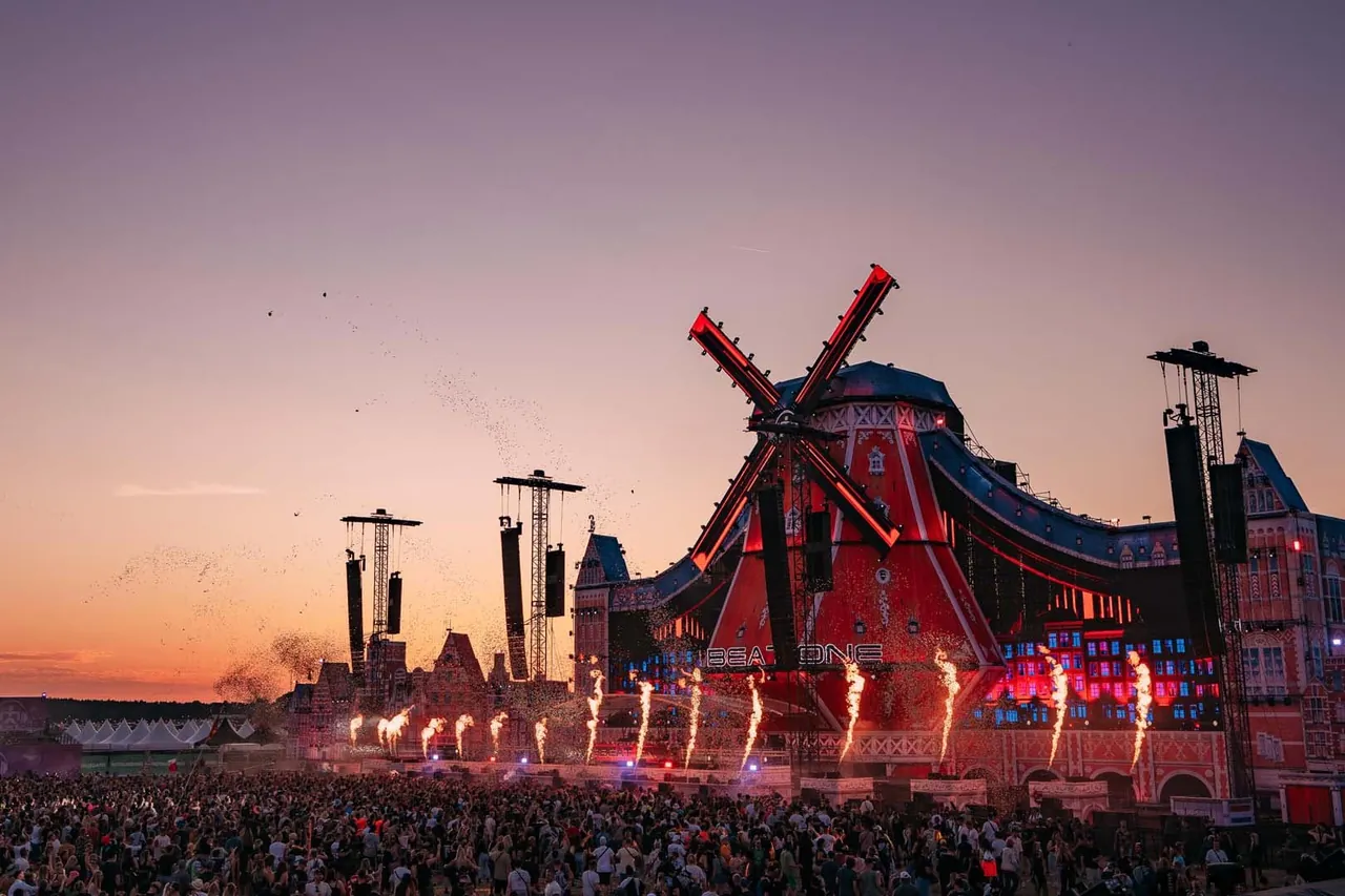 The Mainstage windmill at dusk, flames lit, in 2026.