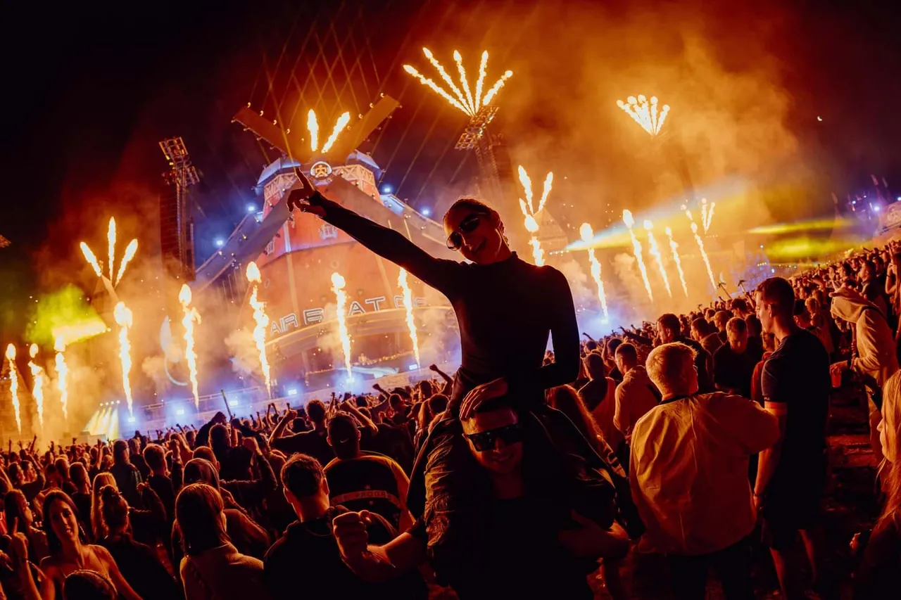 A festivalgoer on someone's shoulders before the blazing Mainstage, one night in 2026.