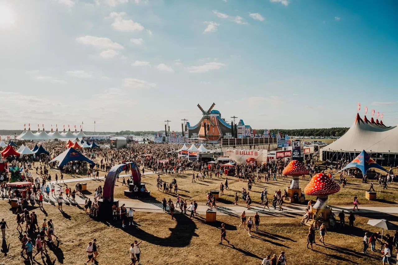 The festival ground on a sunny afternoon in 2026, among giant mushrooms and big tops, with the Mainstage in the distance.