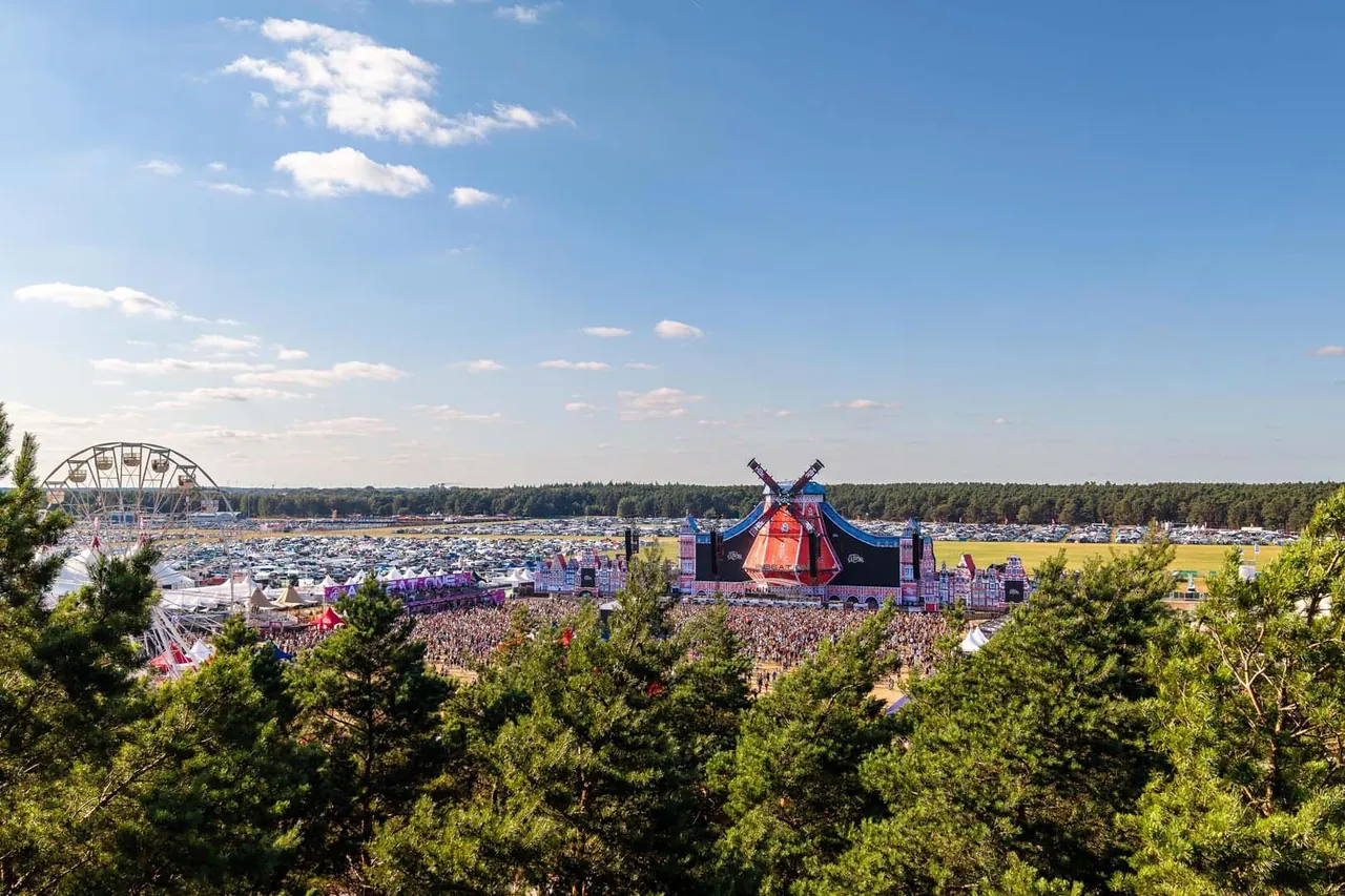 Elevated view of the Neustadt-Glewe airfield in 2026: the windmill-shaped Mainstage, the Ferris wheel and the campsite stretching to the forest.
