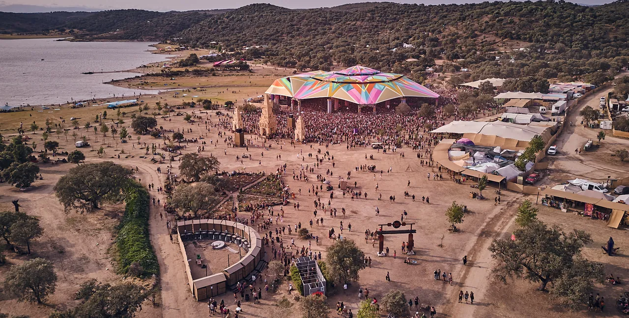 Vue de drone sur le site du festival, ses chemins de terre, ses chênes et le lac en arrière-plan.