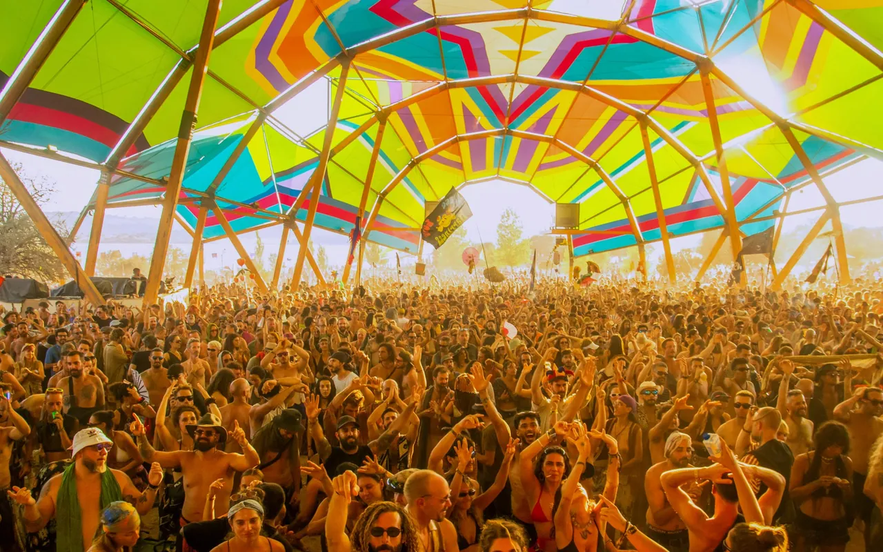 L'Alchemy Circle sous sa structure en bois et ses toiles multicolores, foule dans la lumière de fin de journée.