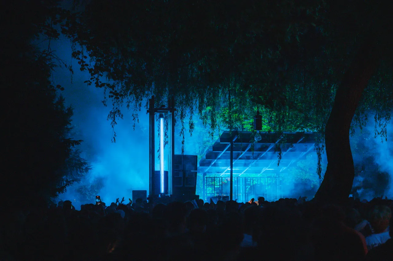 La serre du Greenhouse illuminée en bleu sous les arbres, le samedi 3 août 2024.