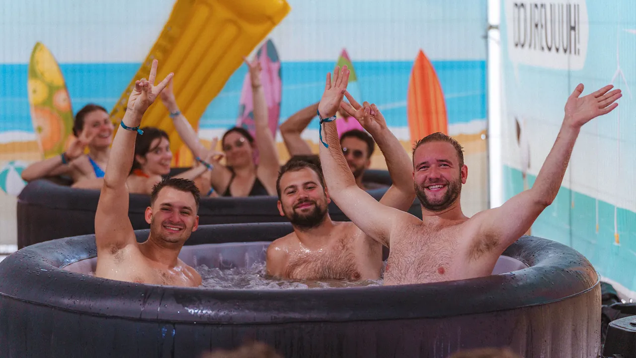 A hot tub at the Dour les Bains campsite, with a beach backdrop and surfboards.