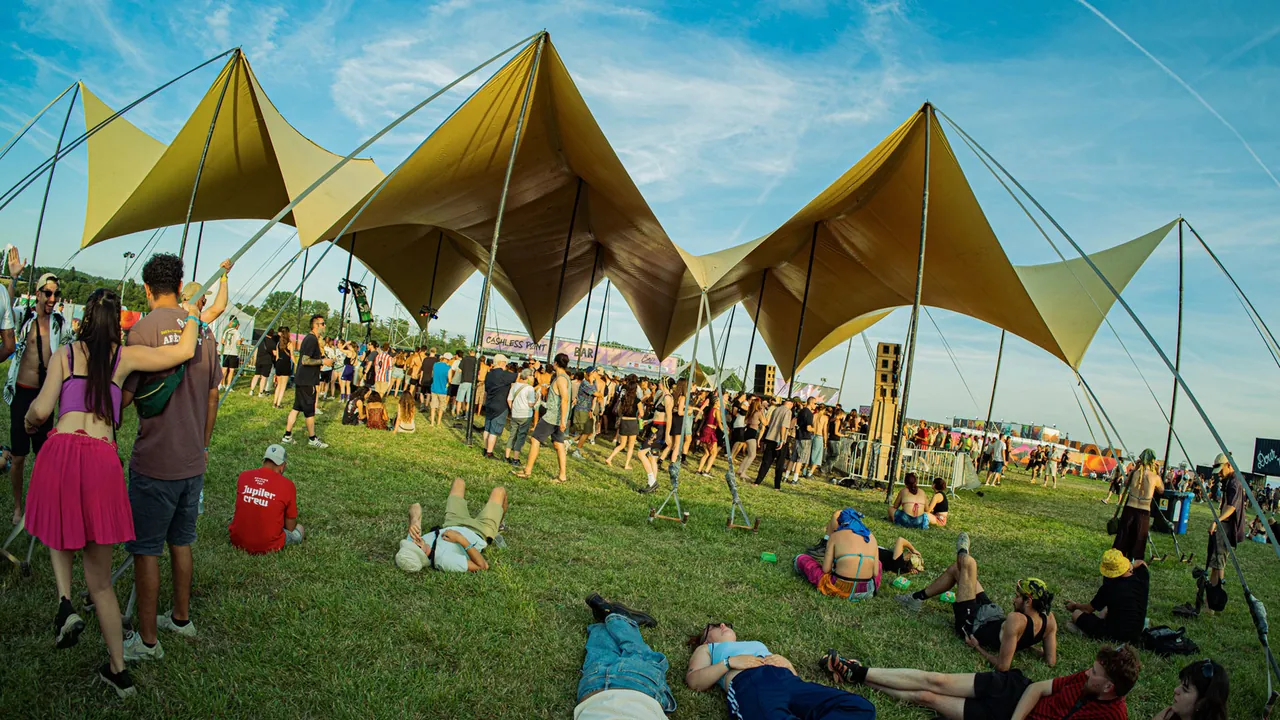 The Dub Corner in broad daylight, its yellow sails and an audience lying in the grass.