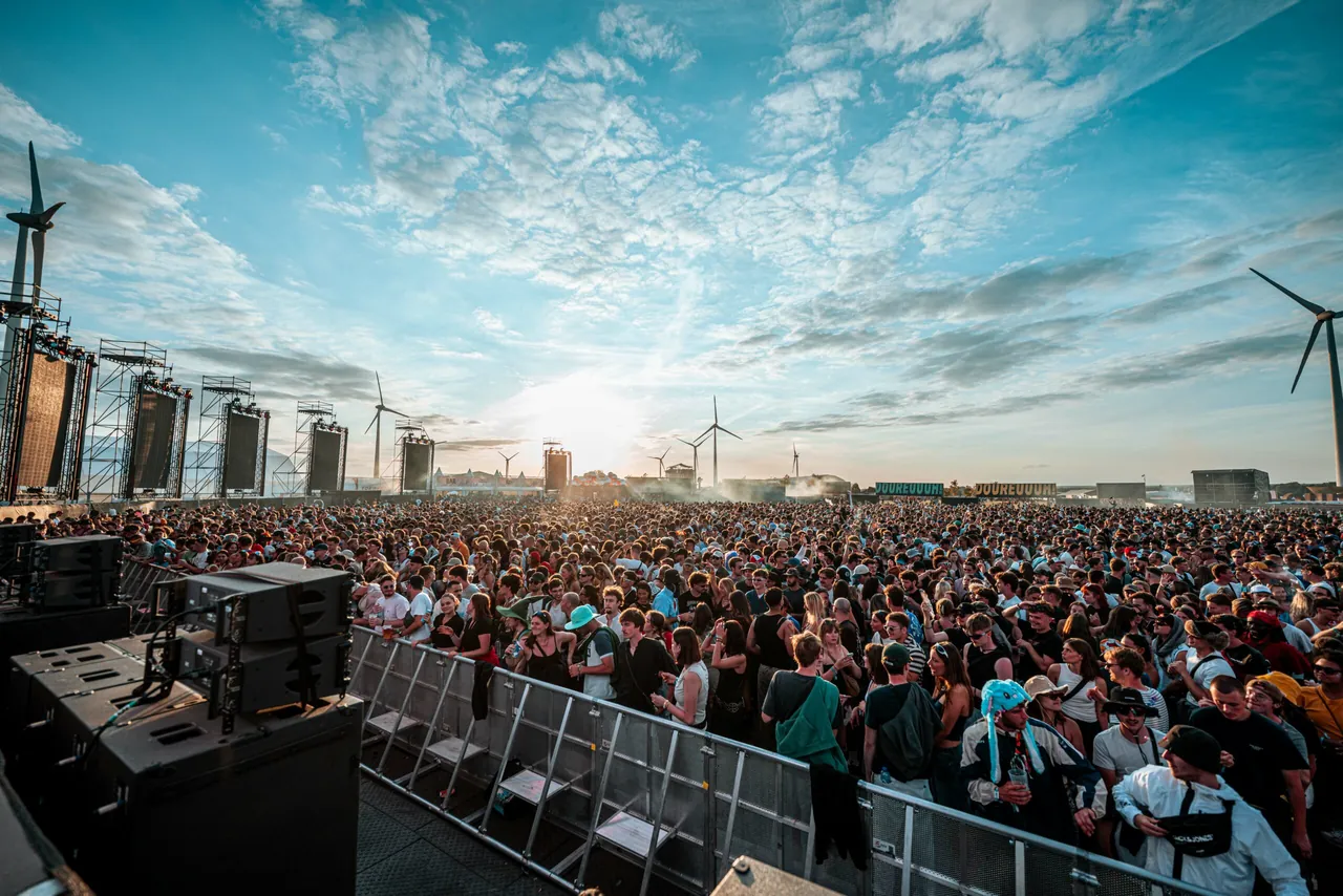 Late afternoon seen from the stage: the crowd and the wind turbines at sunset, 19 July 2025.