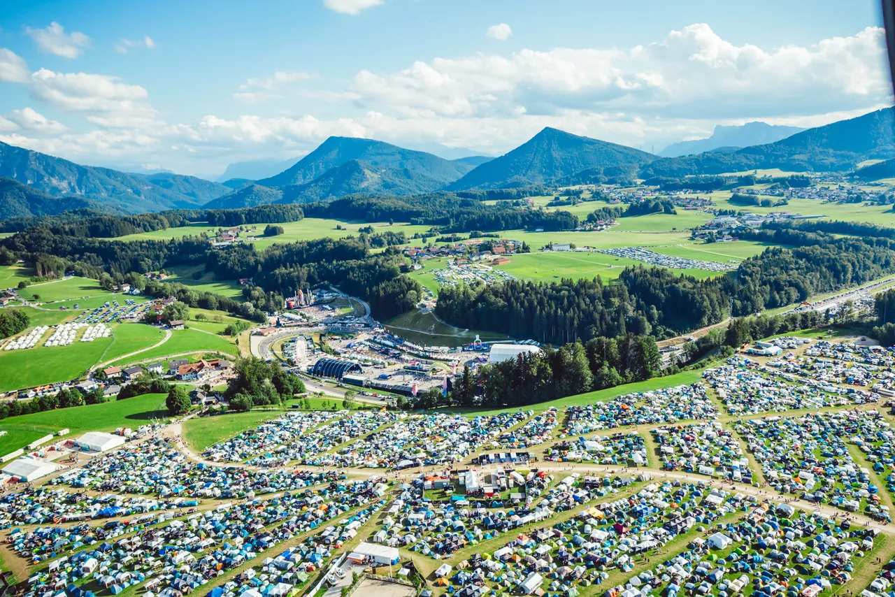 Vue aérienne des campings et du Salzburgring, le 9 juillet 2026, avec les montagnes du Salzkammergut au fond.