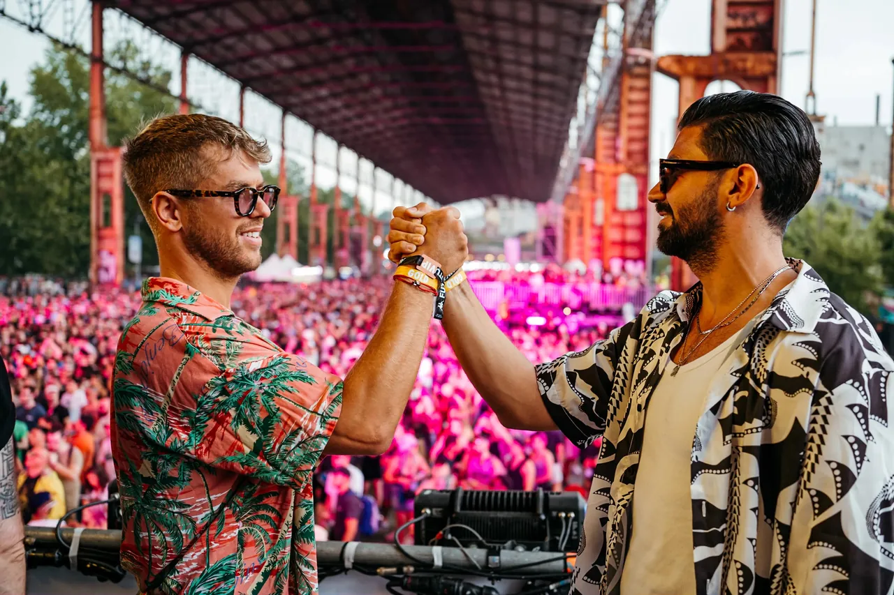 Two artists greet each other behind the decks, under the roof of the Futur Stage, in 2023.