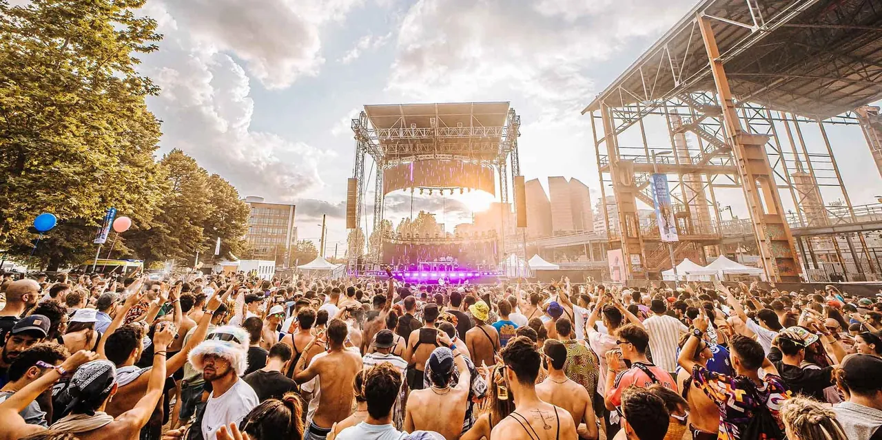 The crowd in the afternoon in front of a stage, next to the steel frame of the former steelworks.