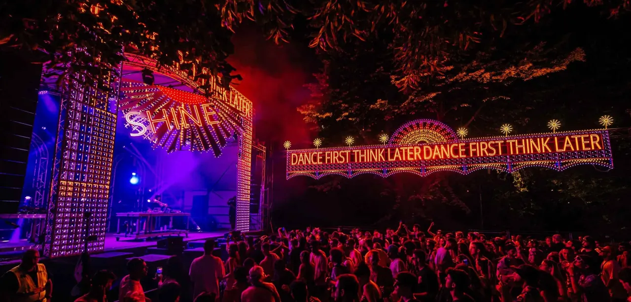The Kosmo Stage at night under the trees, with the "Dance First Think Later" light installation.