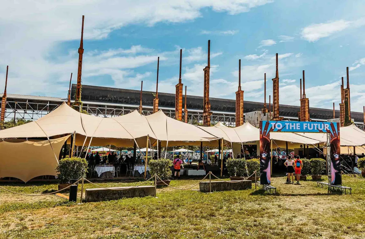 The VIP area and its tents, with the "To the Futur" arch in front of the steelworks pillars.