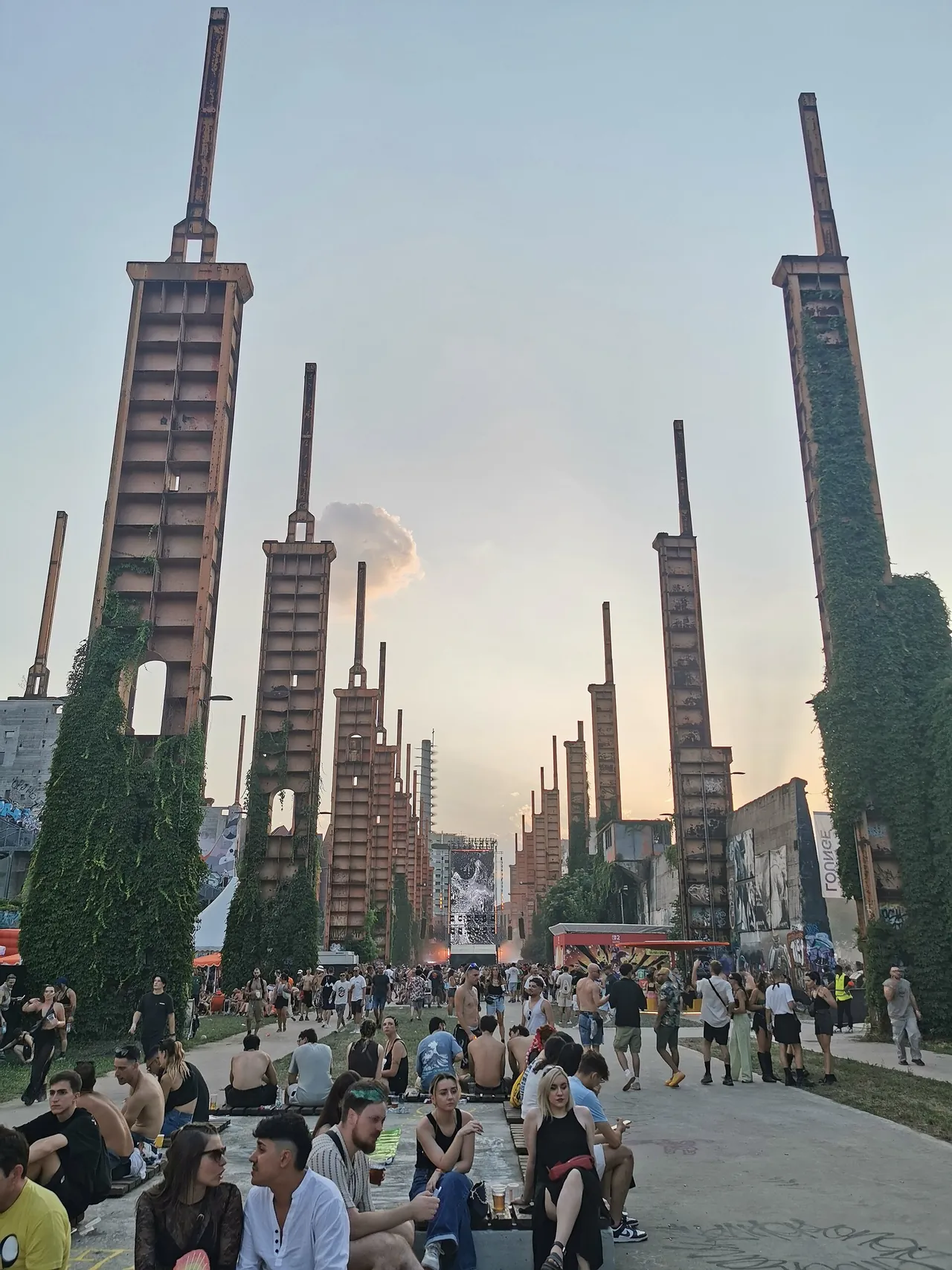 Festivalgoers sitting between the ivy-covered steel pillars near the Voyager Stage, on 4 July 2025.
