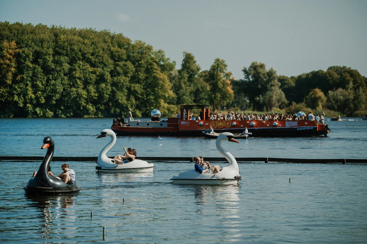 Pédalos en forme de cygne sur le Sloterplas, le bateau-scène Talent Cruise en arrière-plan, le dimanche 10 août 2025.
