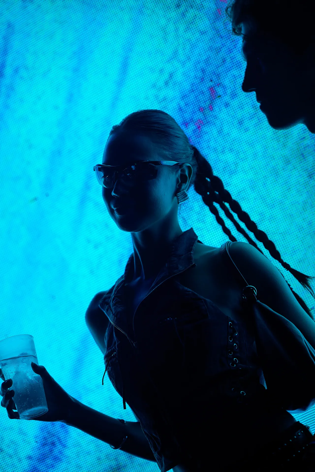 Une festivalière en contre-jour devant un écran LED bleu.