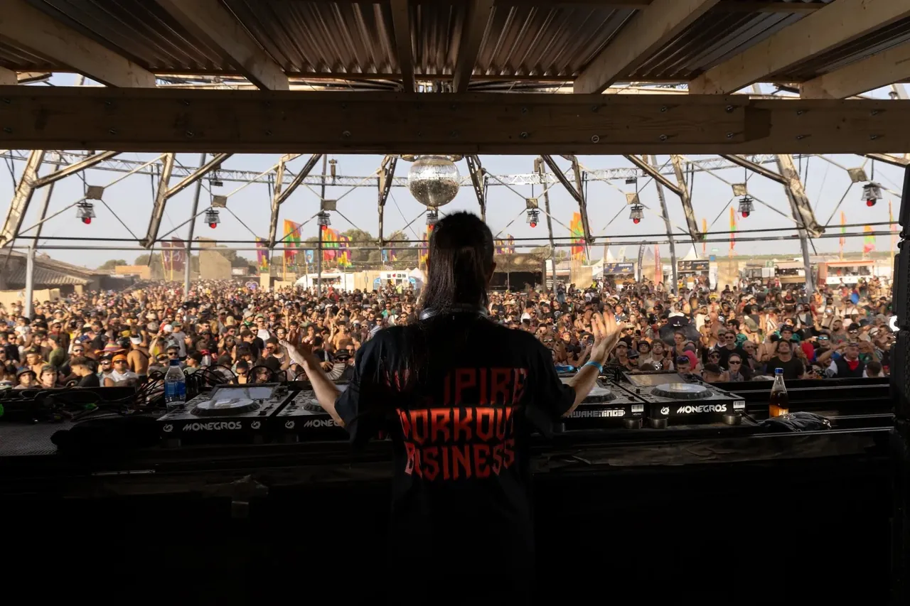 A DJ facing the crowd under the same dome, decks branded Monegros and Awakenings.