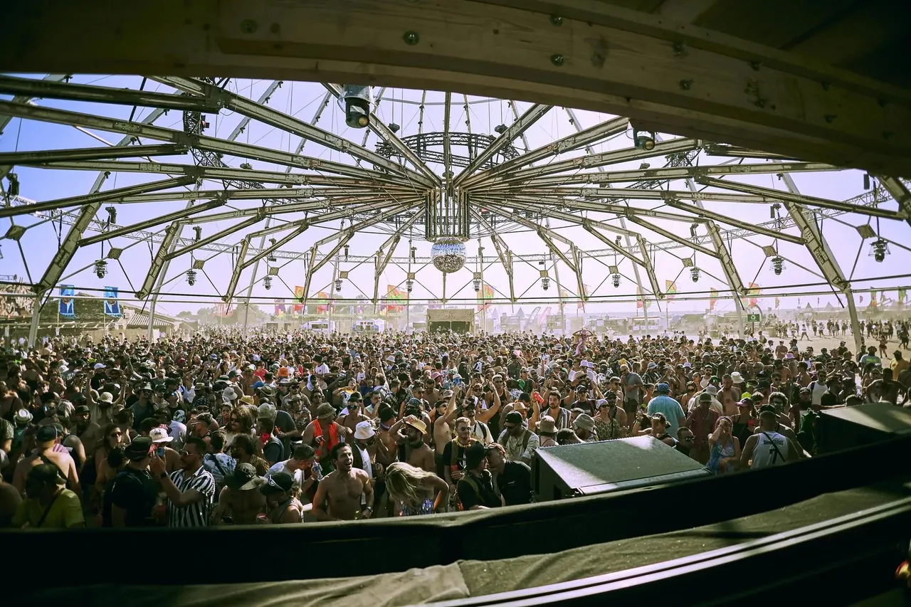 The crowd under the radial-frame dome with its mirror ball, seen from the DJ booth.