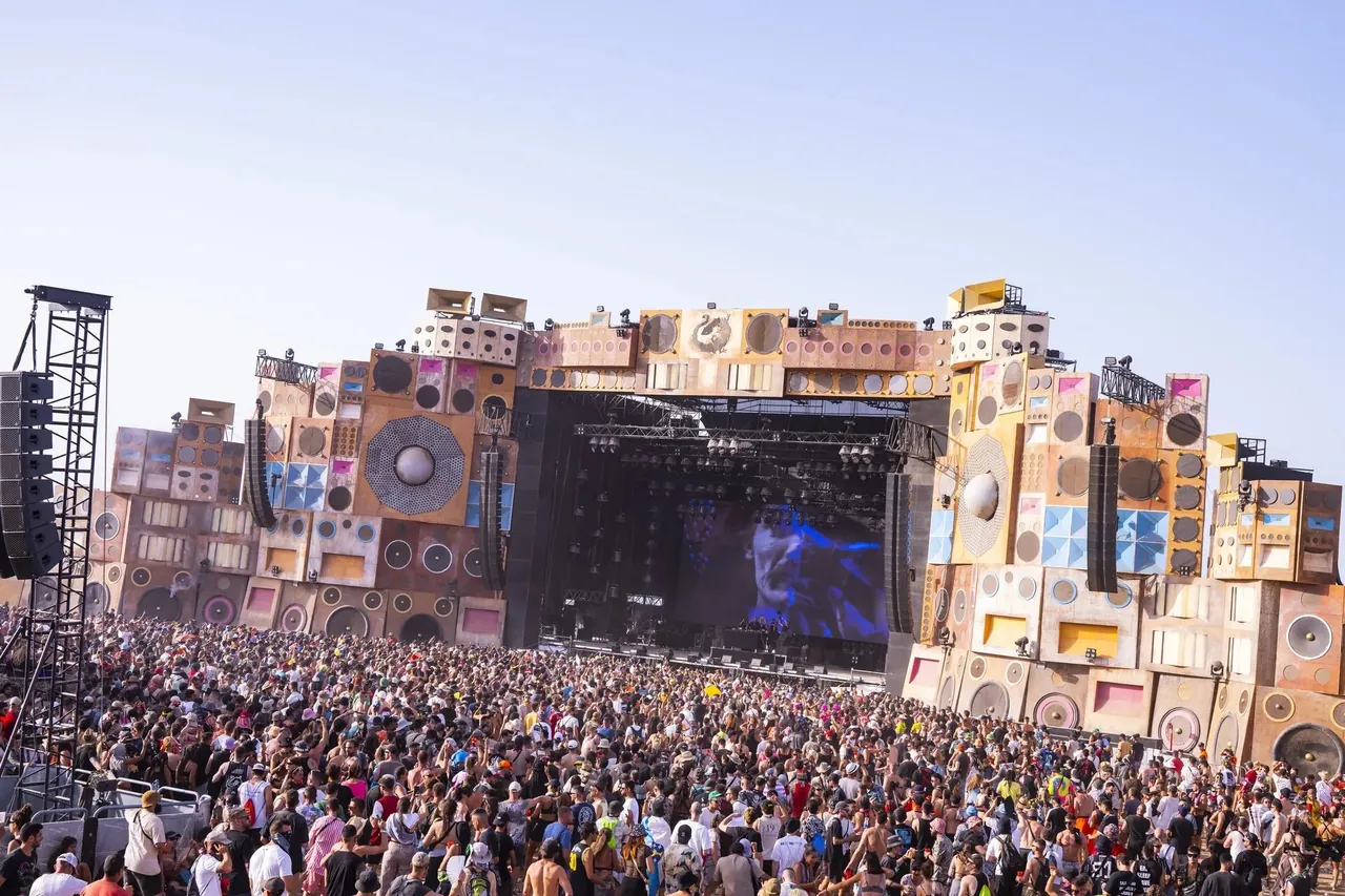 The Sound System Temple, the main stage built as a wall of 1990s-style speakers, in daylight before the crowd.