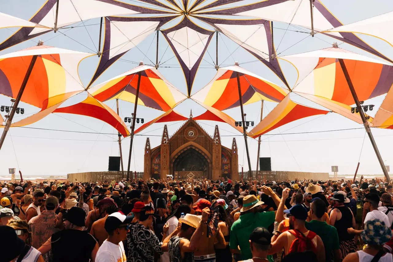The Techno Cathedral in daylight: a neo-Gothic wooden facade under large shade sails.