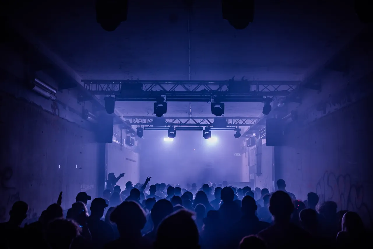À l'intérieur d'un bunker transformé en club en 2023 : murs de béton brut, fumée et lumière bleue.