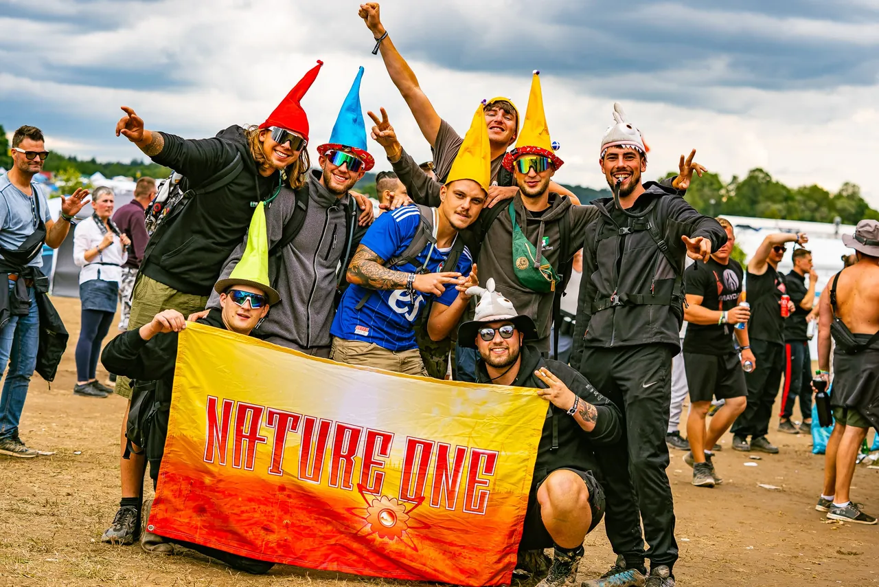 Une bande de campeurs avec son drapeau Nature One au CampingVillage, en 2023.