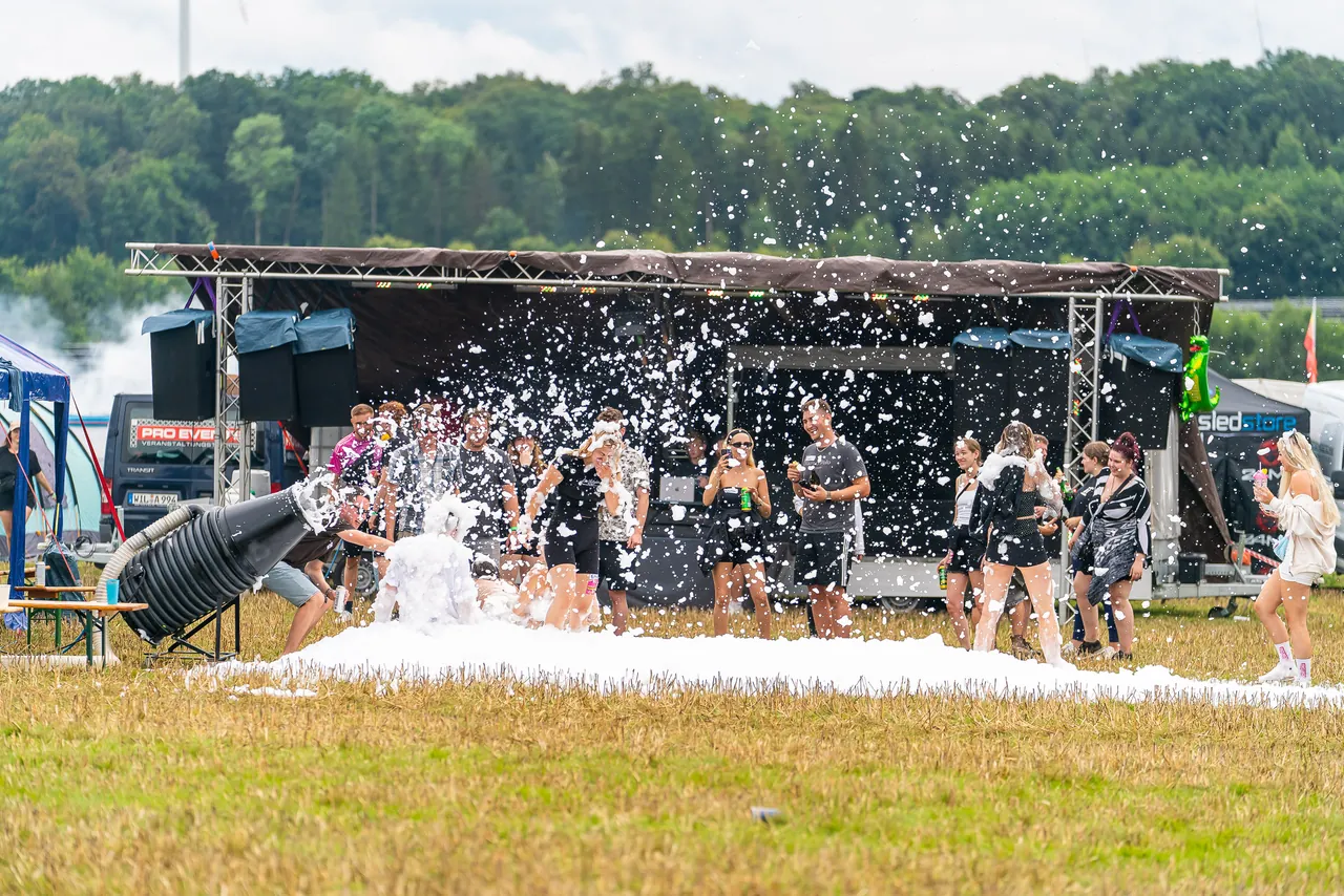 Un CampFloor monté par des campeurs en 2024 : une petite scène sur remorque et un canon à mousse dans le pré.