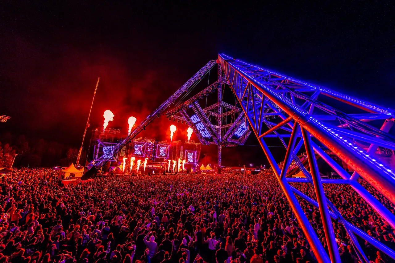 L'OpenAirFloor en 2023 : la pyramide de structures éclairée en bleu, les flammes de la scène et la foule.