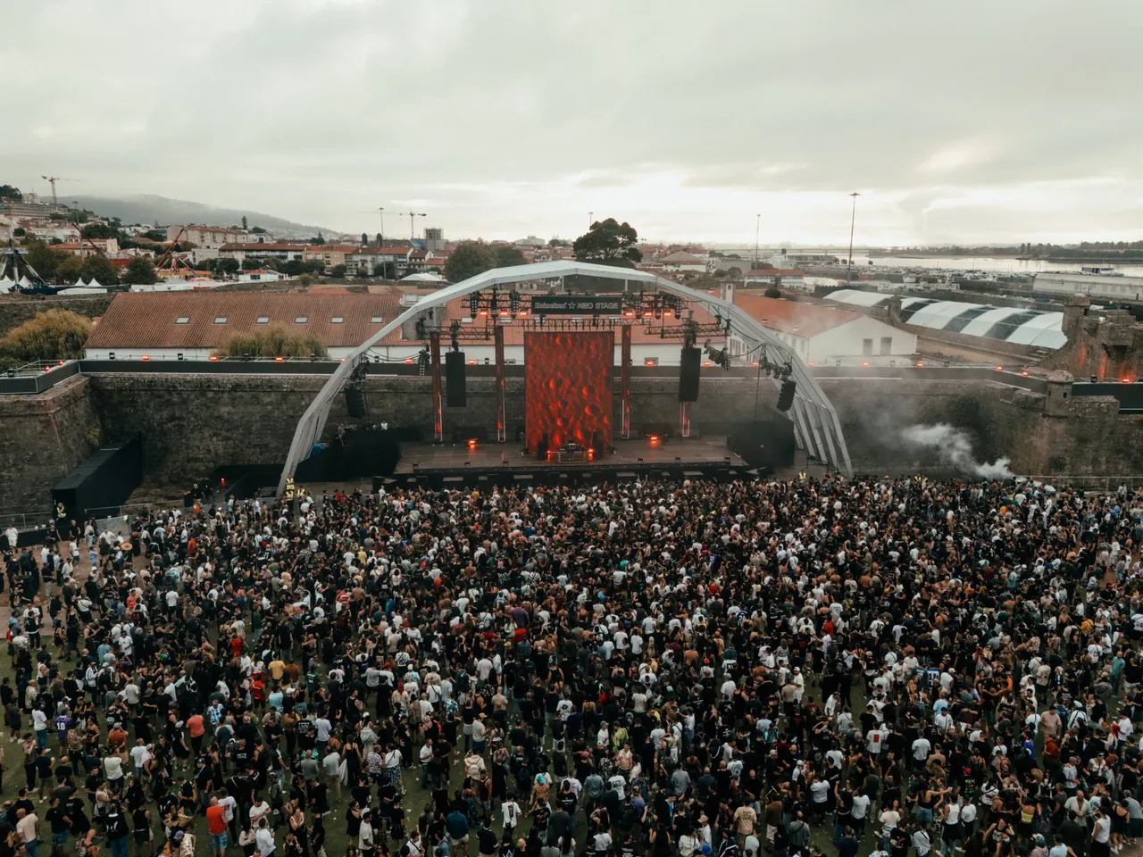 The Neo Stage from above in the early morning of Sunday 9 August 2026, during Jeff Mills' set, between the walls of Forte de Santiago da Barra and the town.