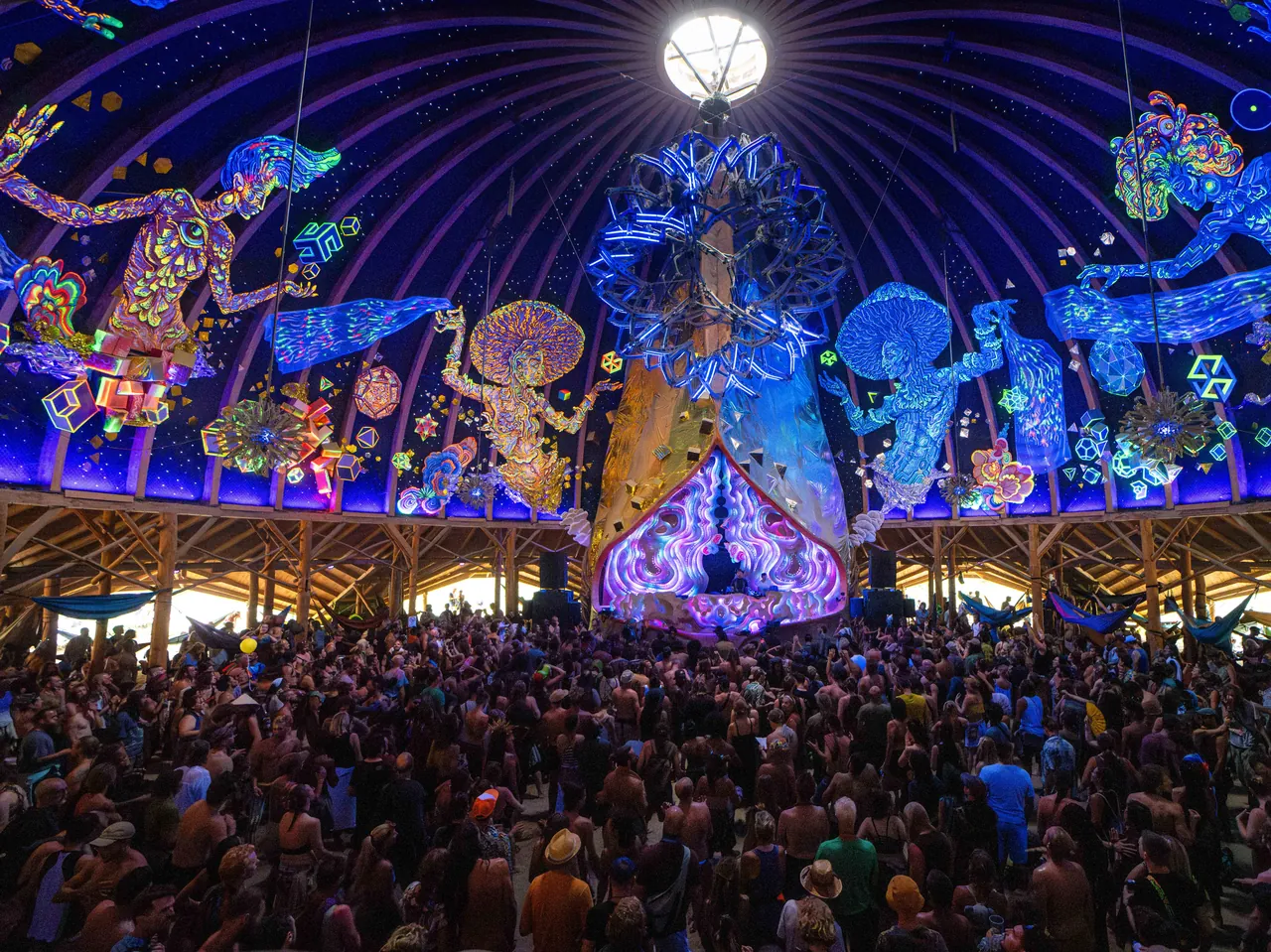 The Dome at night: its dome painted with fluorescent figures above the crowd, in 2023.