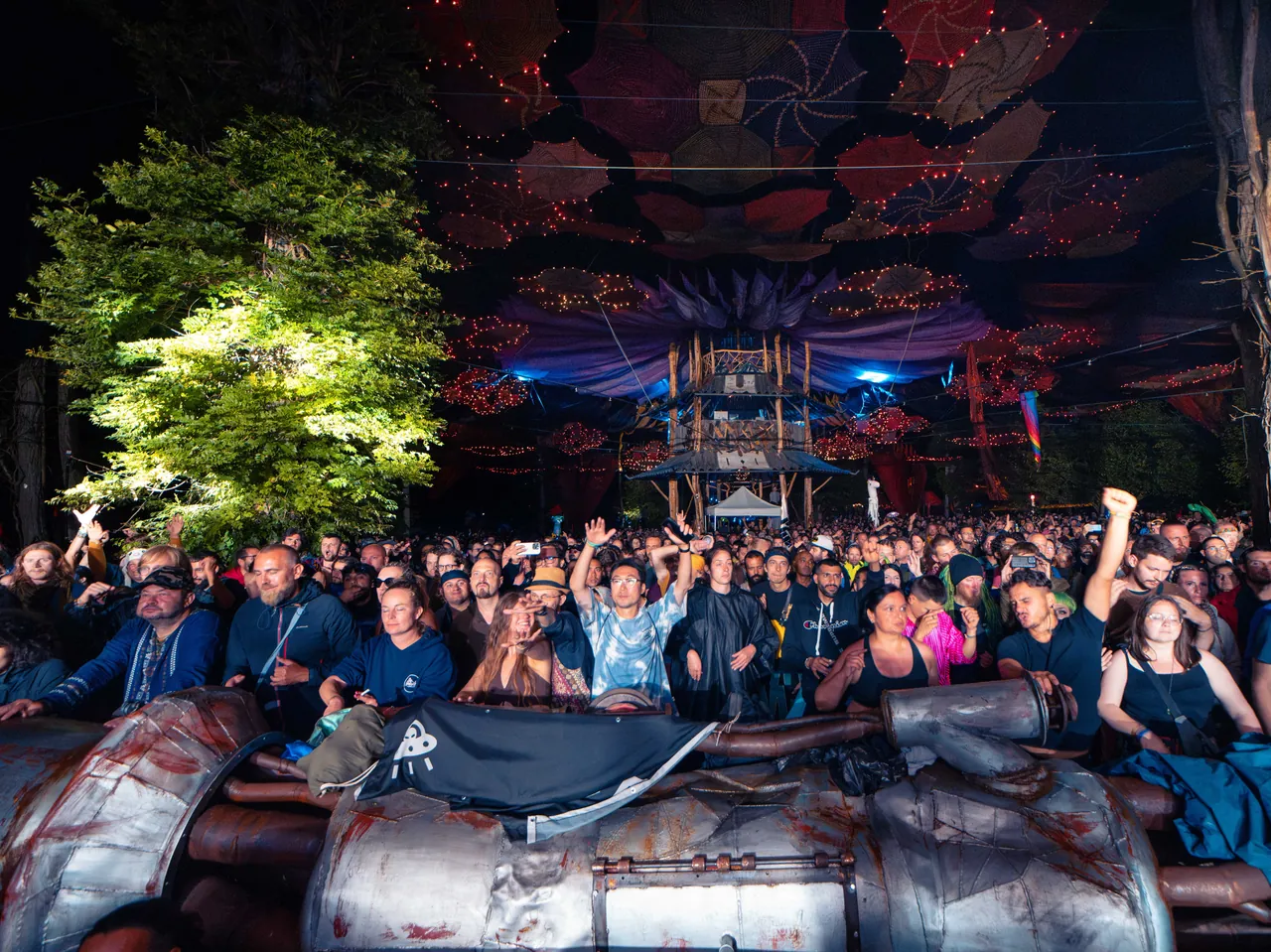 The Ozora Stage at night, the crowd packed behind the decorated barrier, in 2023.