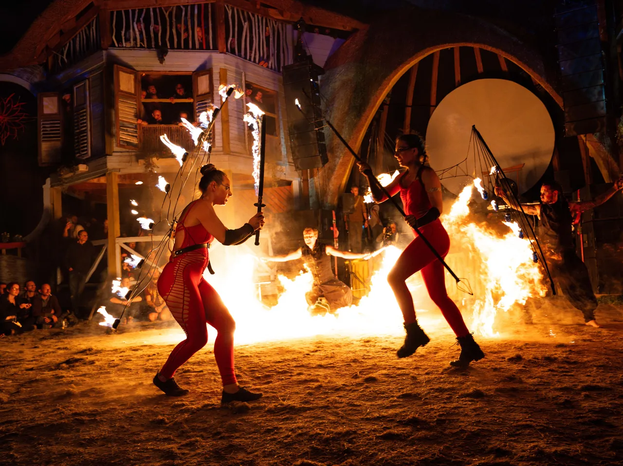 A night-time fire show in front of a wooden set, in 2023.