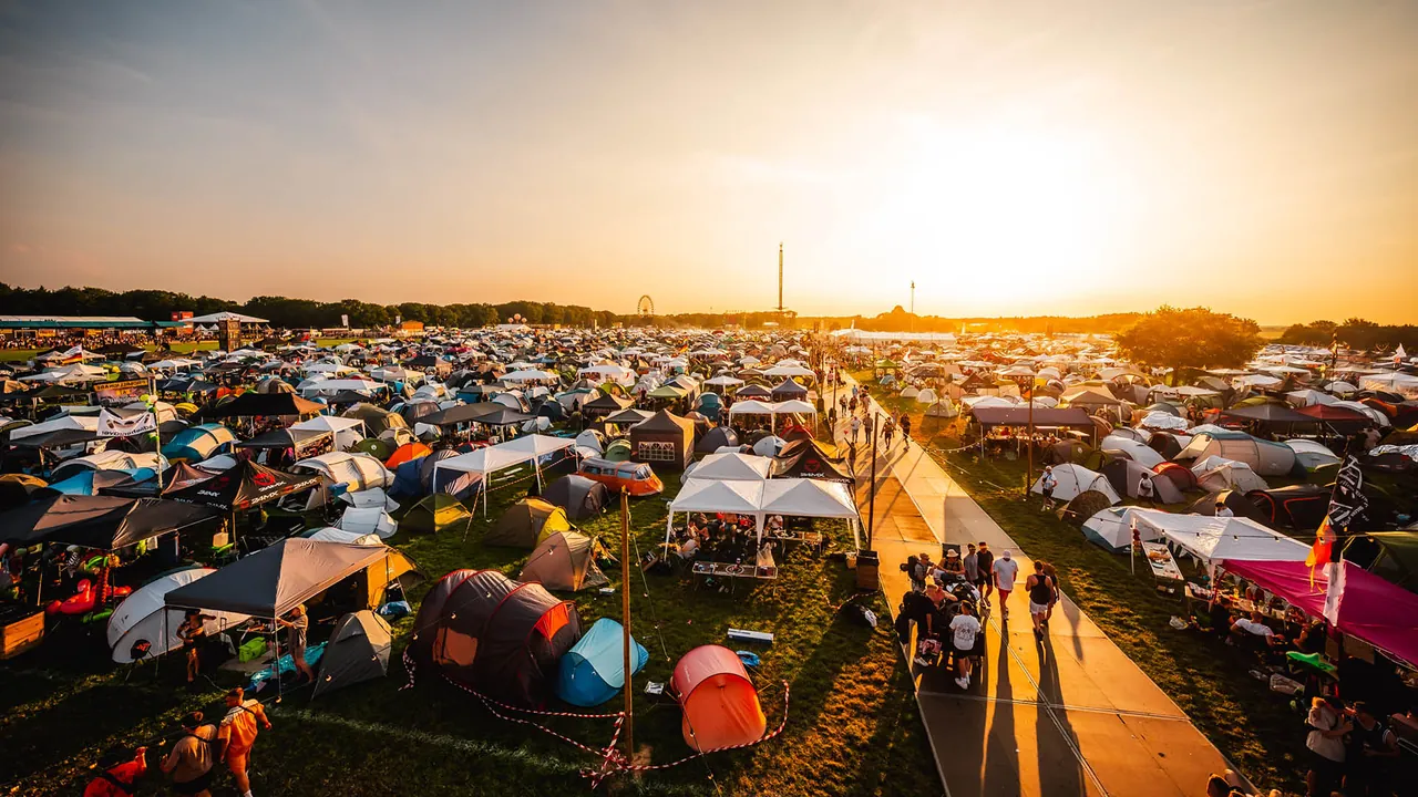 The campsite at sunset, tents and gazebos along the paths.