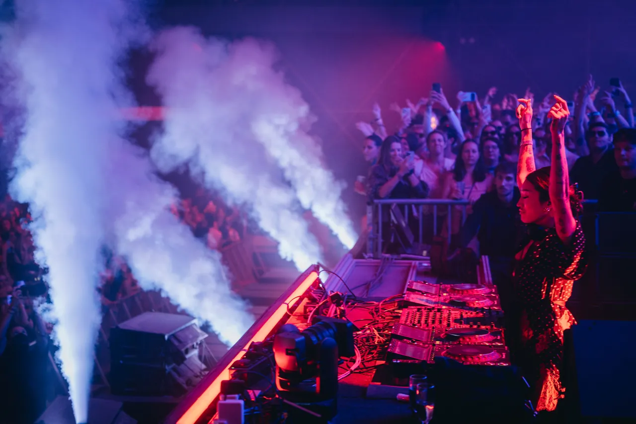 Peggy Gou aux platines face au public, entre deux jets de CO2, le vendredi 14 août 2026 (BOLT Night Stage selon le programme publié).