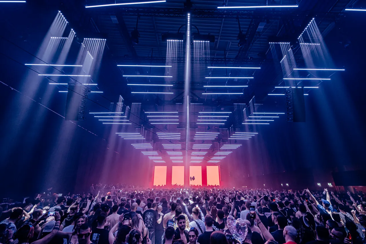 Un floor entier quadrillé de barres lumineuses suspendues, au-dessus d'une salle comble, édition d'avril 2023.