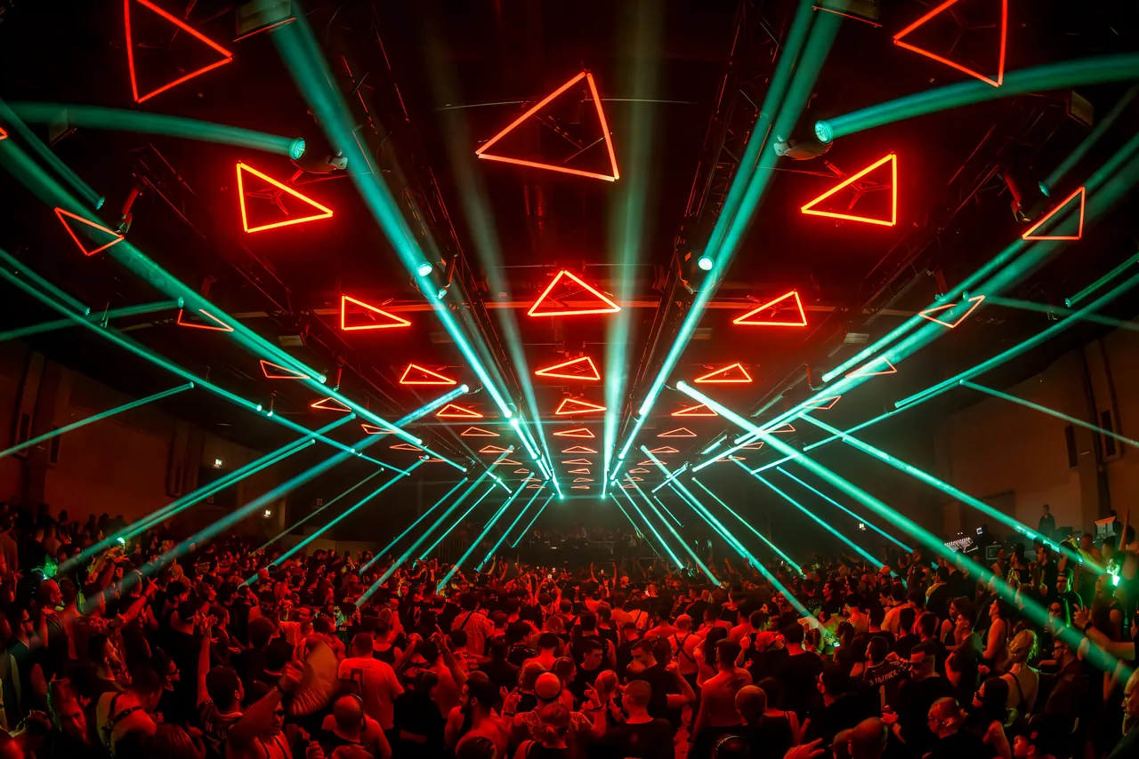 Triangles lumineux et lasers verts au-dessus d'une foule compacte, à l'édition « Two Days | Two Celebrations » d'octobre 2024 à Mannheim.
