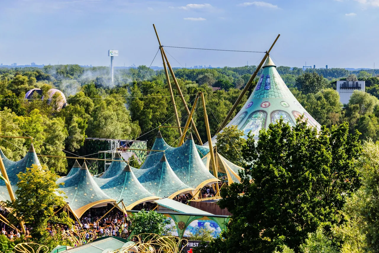Vue en hauteur des chapiteaux décorés noyés dans les arbres de De Schorre (2024).