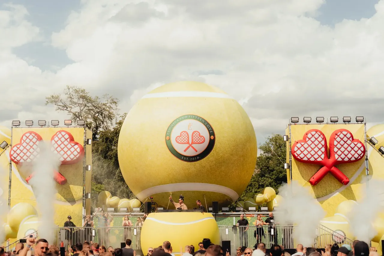 A stage dressed with giant tennis balls and inflatable rackets.