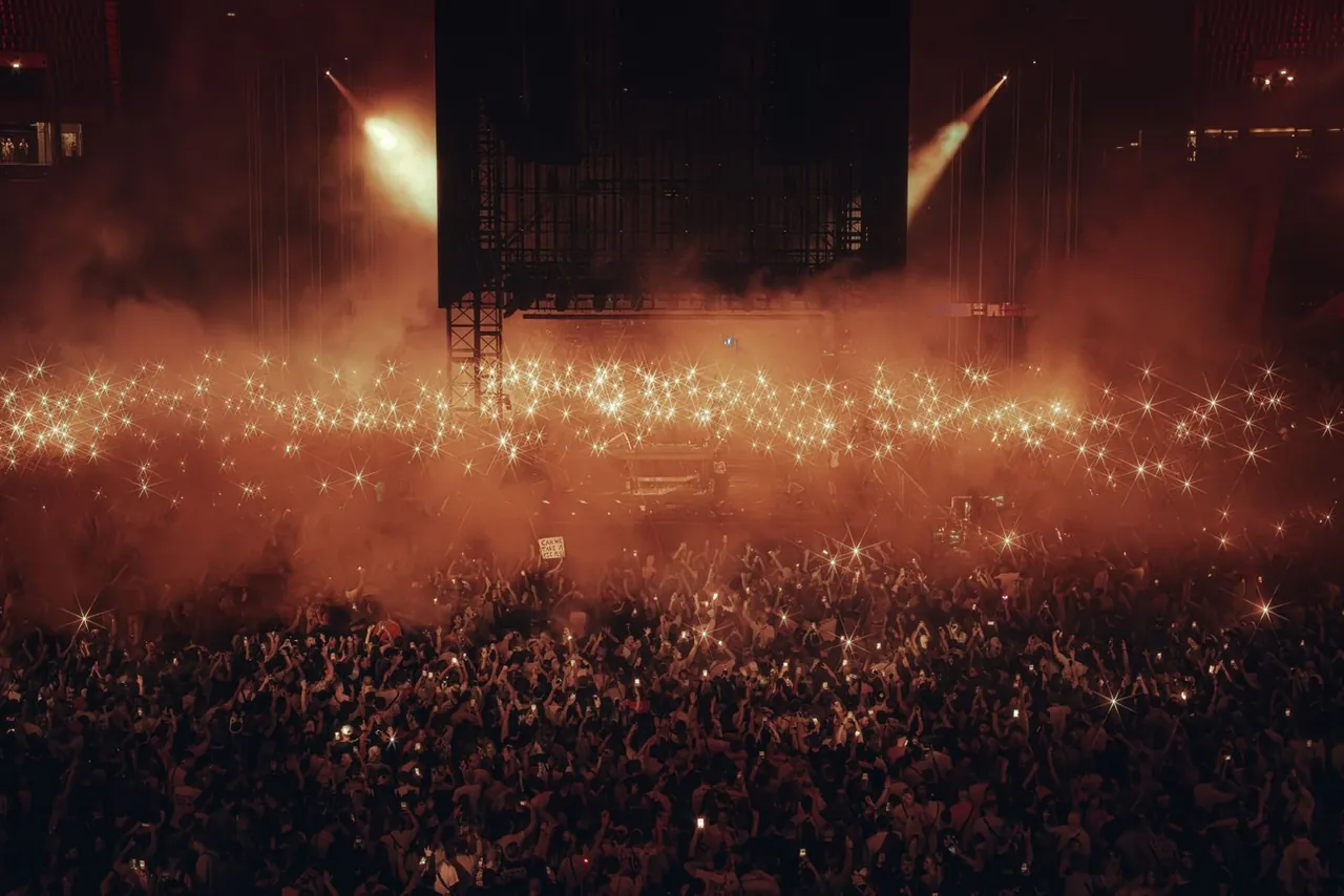The stadium bathed in orange smoke and lit by thousands of phones.