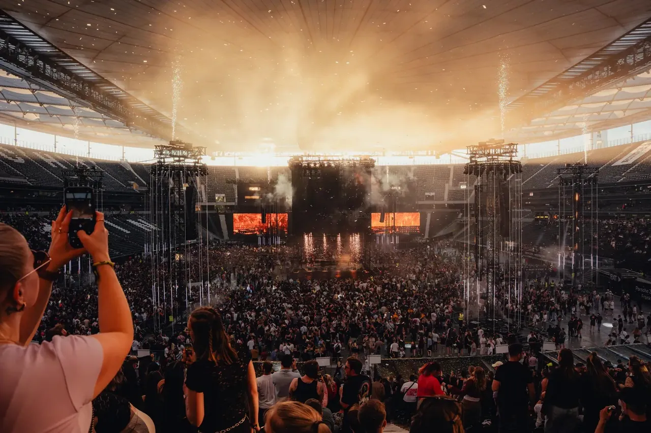 The crowd around the centre stage inside the stadium bowl in the late afternoon, under the roof.