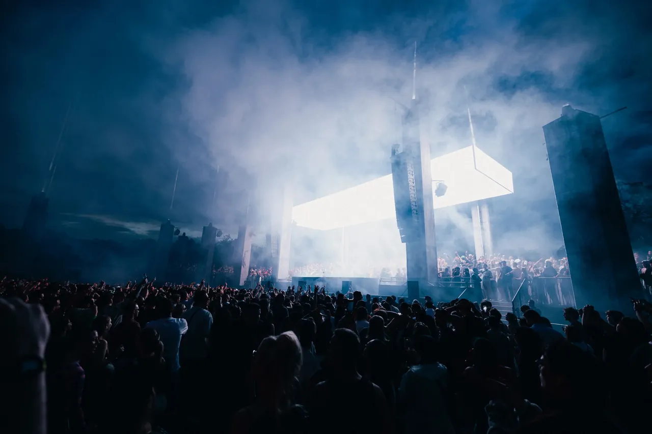 The UNREAL stage at night: a block of light hung between concrete pillars, wrapped in smoke.