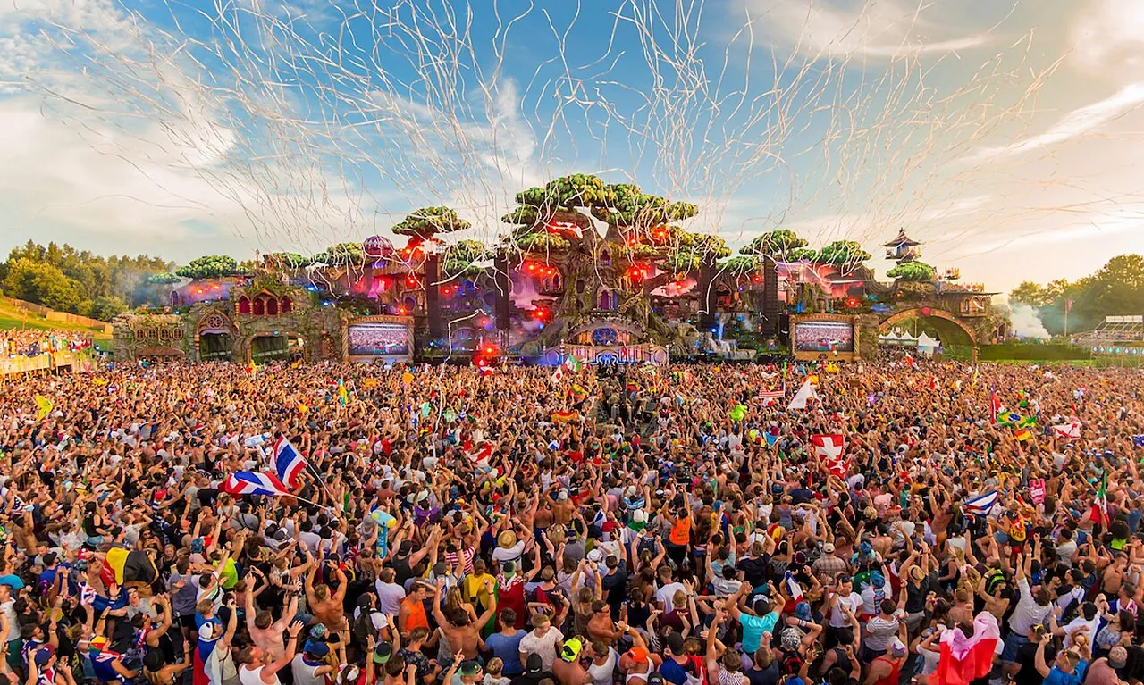 The Tomorrowland 2016 main stage shaped like a forest of giant trees, under a shower of streamers, in front of a huge crowd waving flags